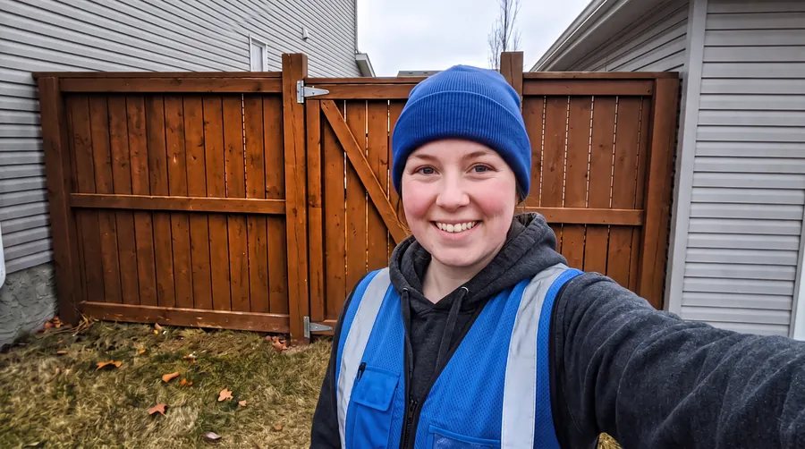 Selfie of a smiling Holy Crap scooper in front of a latched backyard gate